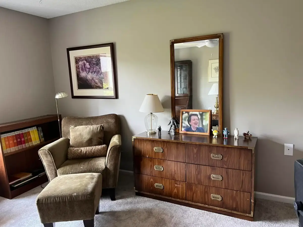 A reading chair with ottoman beside a wood dresser and mirror
