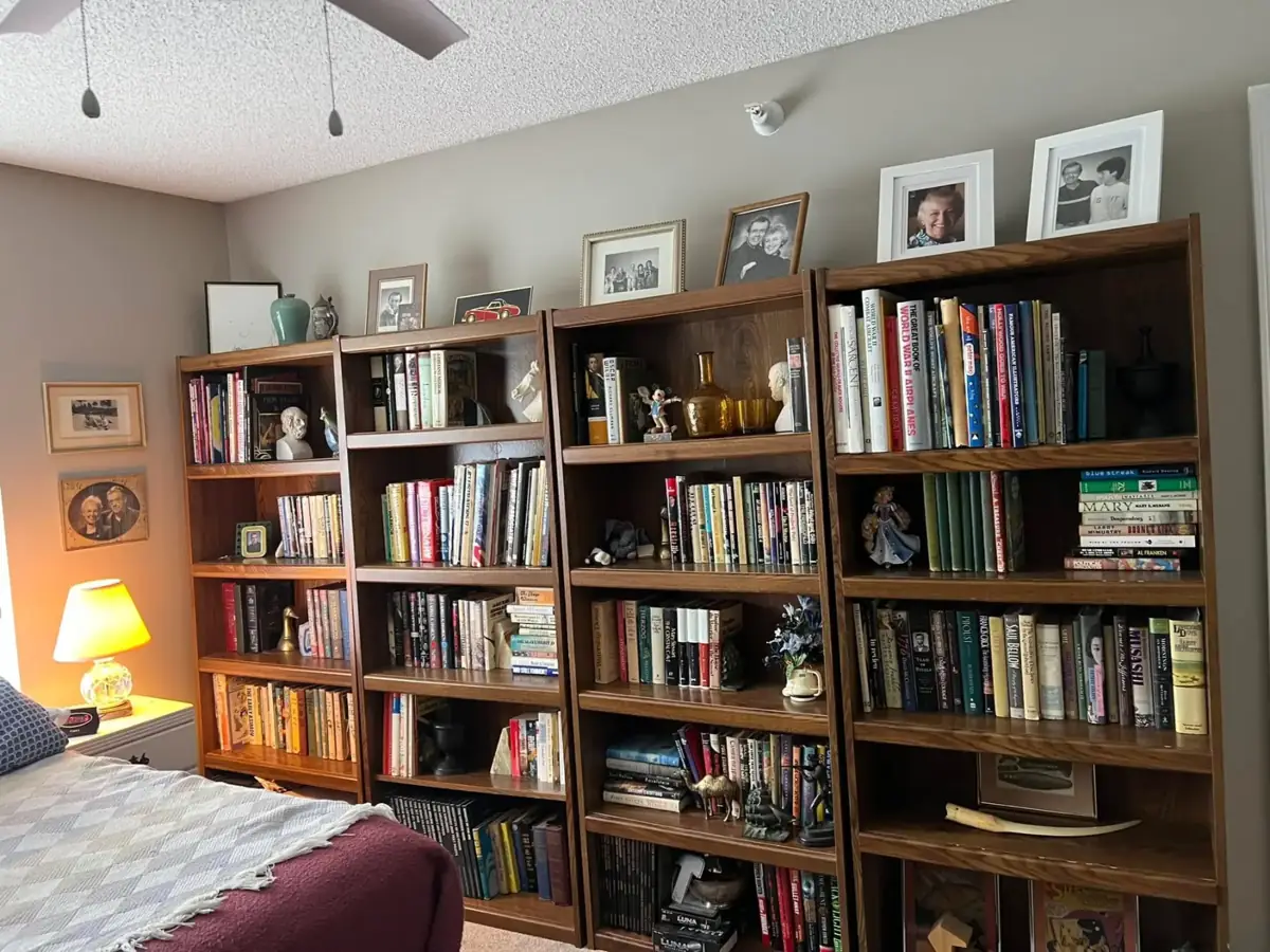 A wall of bookshelves filled with books and framed family photos