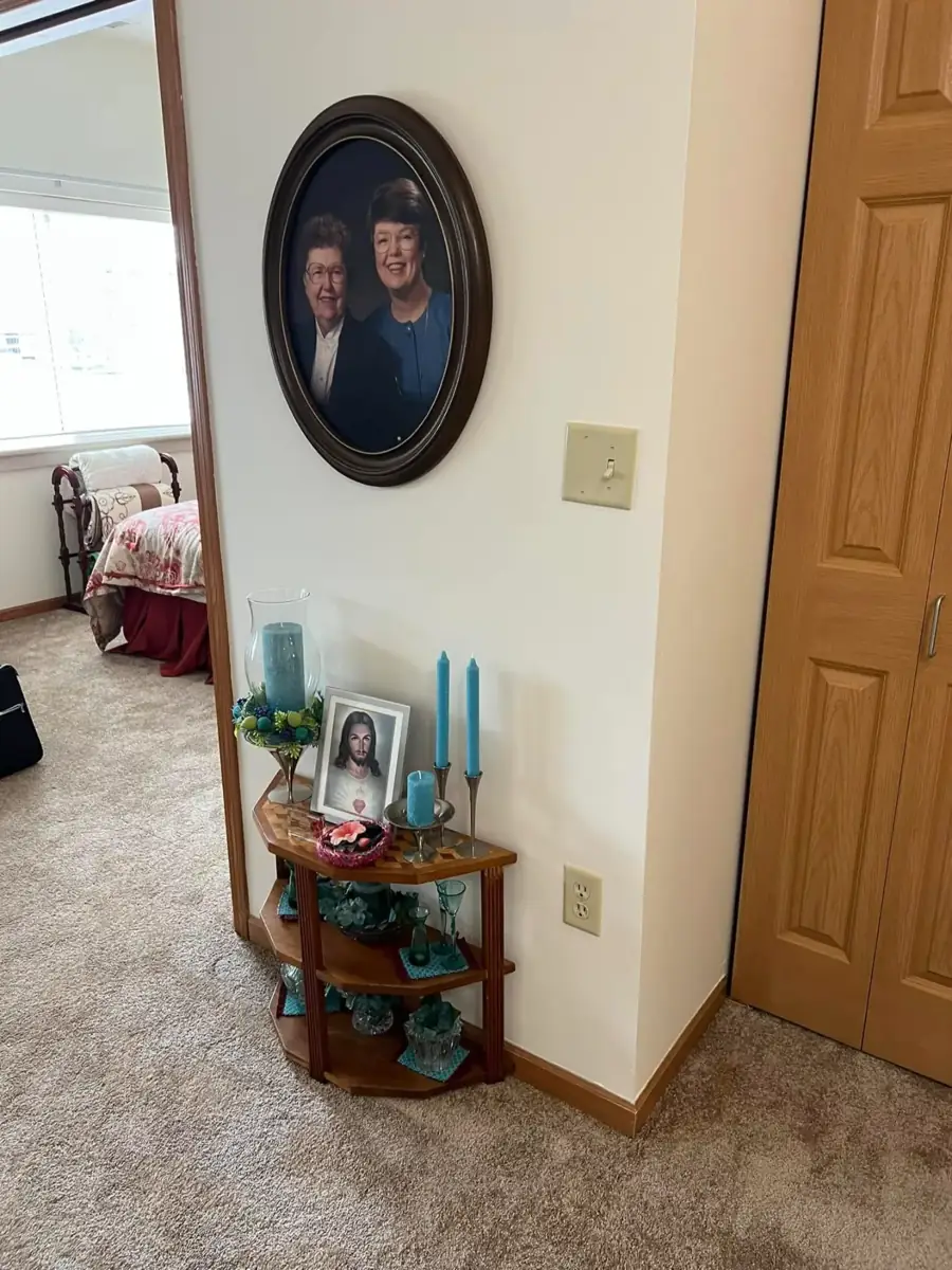 A hallway corner shelf with candles below a framed oval portrait