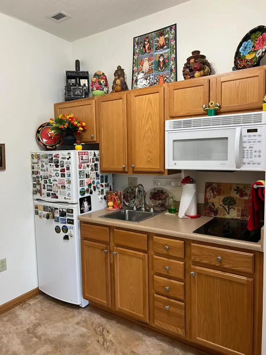 A small kitchen with oak cabinets and a refrigerator covered in magnets