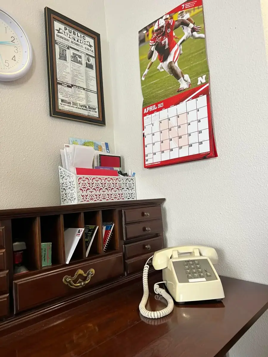 A desk with a cream telephone, mail organizer and a football calendar