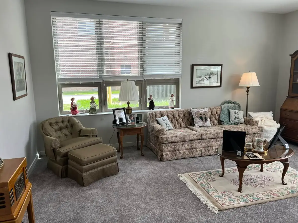 A living room with a tufted sofa, armchair with ottoman and framed art